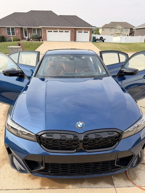 Blue BMW M340i freshly detailed in a driveway with both front doors open